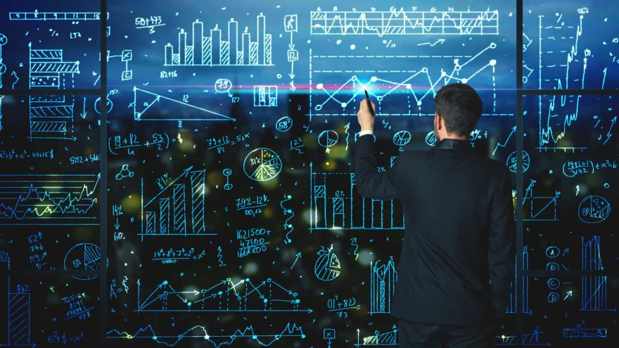 Ein mann steht vor einer Tafel mit vielen Statistiken und Diagrammen