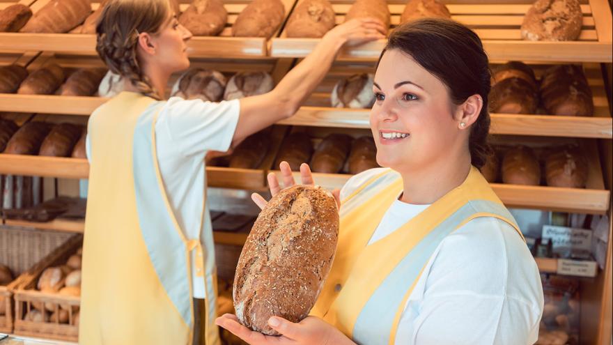 Verkäuferin in einer Bäckerei hält Brot in der Hand