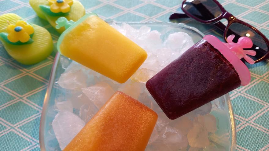 Auf einer Schüssel mit Eiswürfeln liegen drei bunte, selbstgemachte Popsicles.