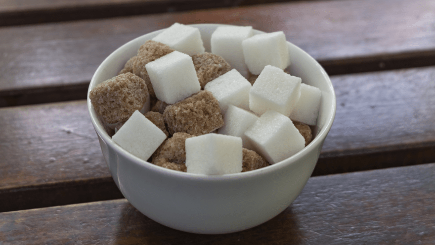 Weiße und braune Zuckerwürfel in einer weißen Schüssel.