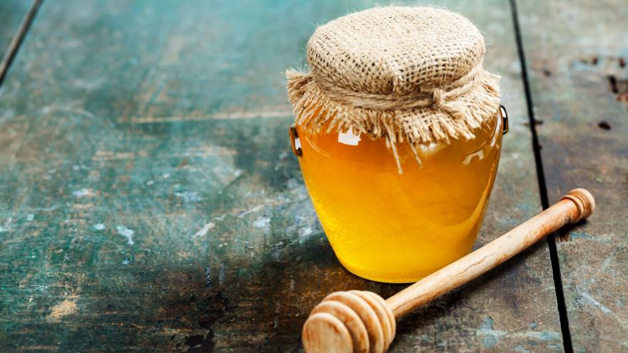 Ein Glas Honig steht auf einem Holztisch.