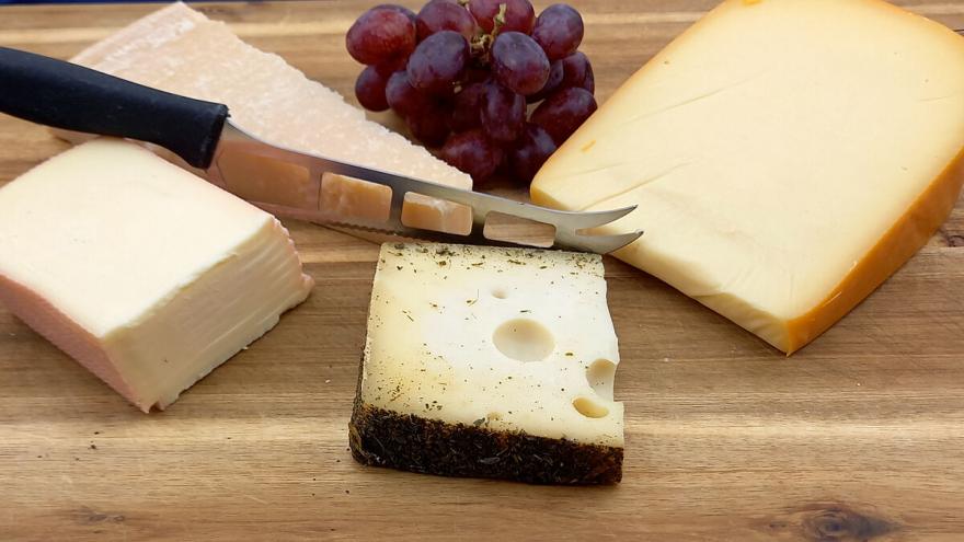 Verschiedene Käse am Stück liegen auf einem Holzbrett.