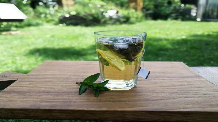 Ein Glas mit Cold Brew Tee steht auf einem Tisch im Garten.