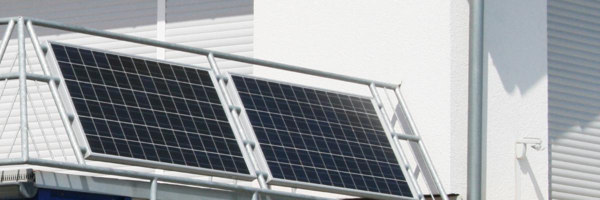 Außen an dem Geländer eines Balkons sind zwei Solarmodule montiert.