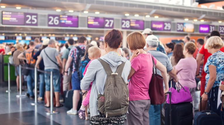 Eine Schlange von Menschen steht vor einem Schalter am Flughafen.